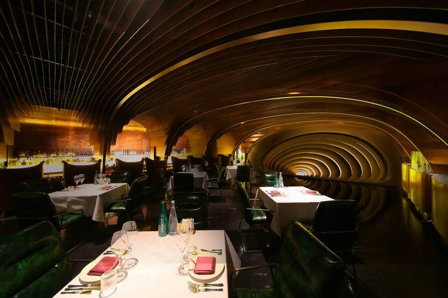Panoramic view of the first-floor dining area, where bronze arch surfaces and cave-like space create a retro, surreal restaurant atmosphere.
