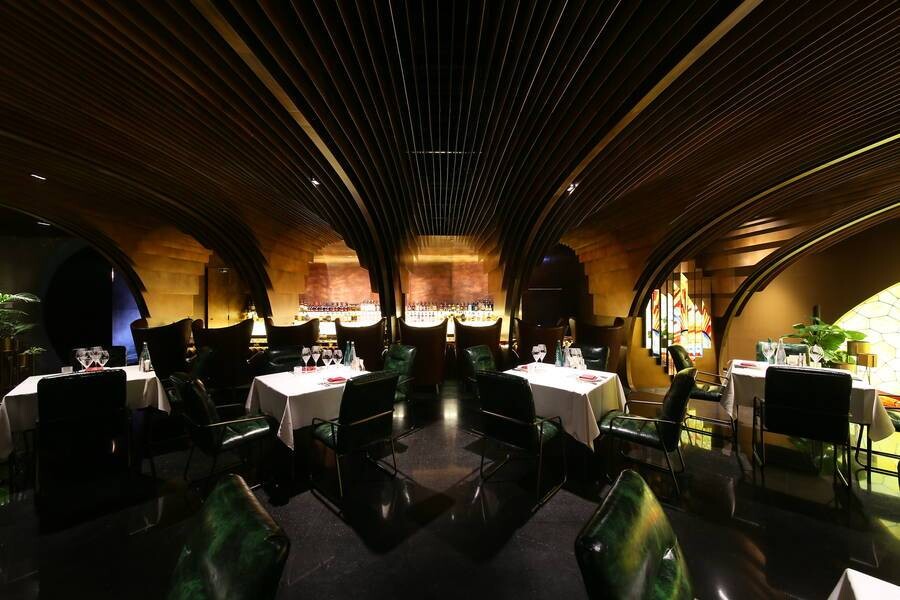 First-floor dining area with continuous arched ceilings and dark seating that strengthen the sense of enclosure.