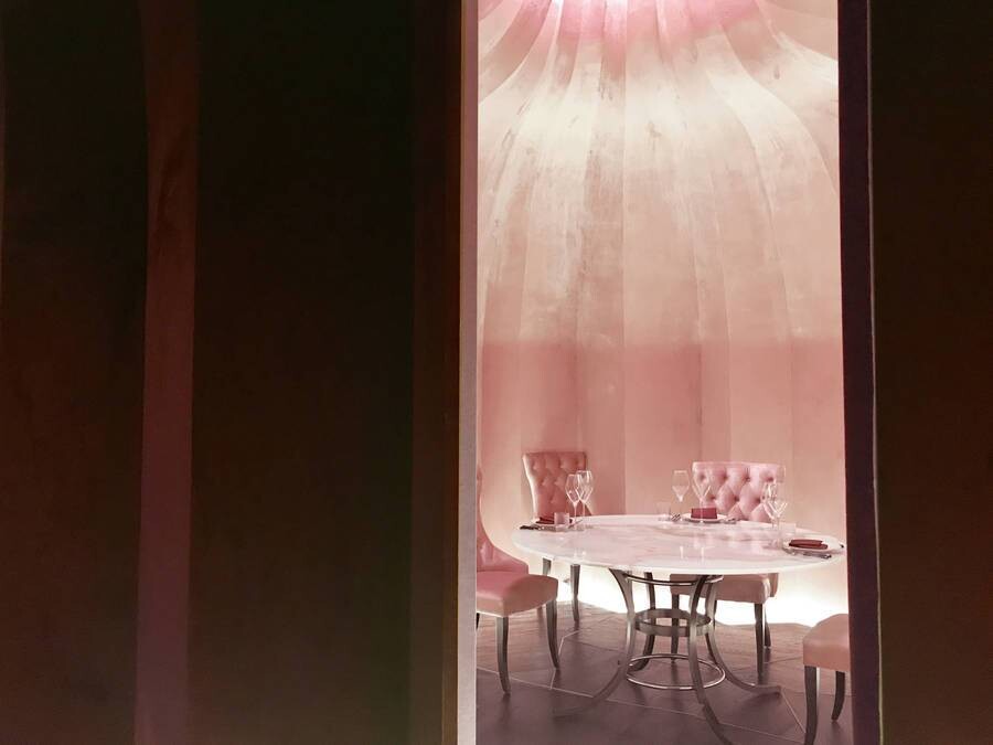 Pink private dining room with curved walls and overhead light forming an independent fantasy dining space.