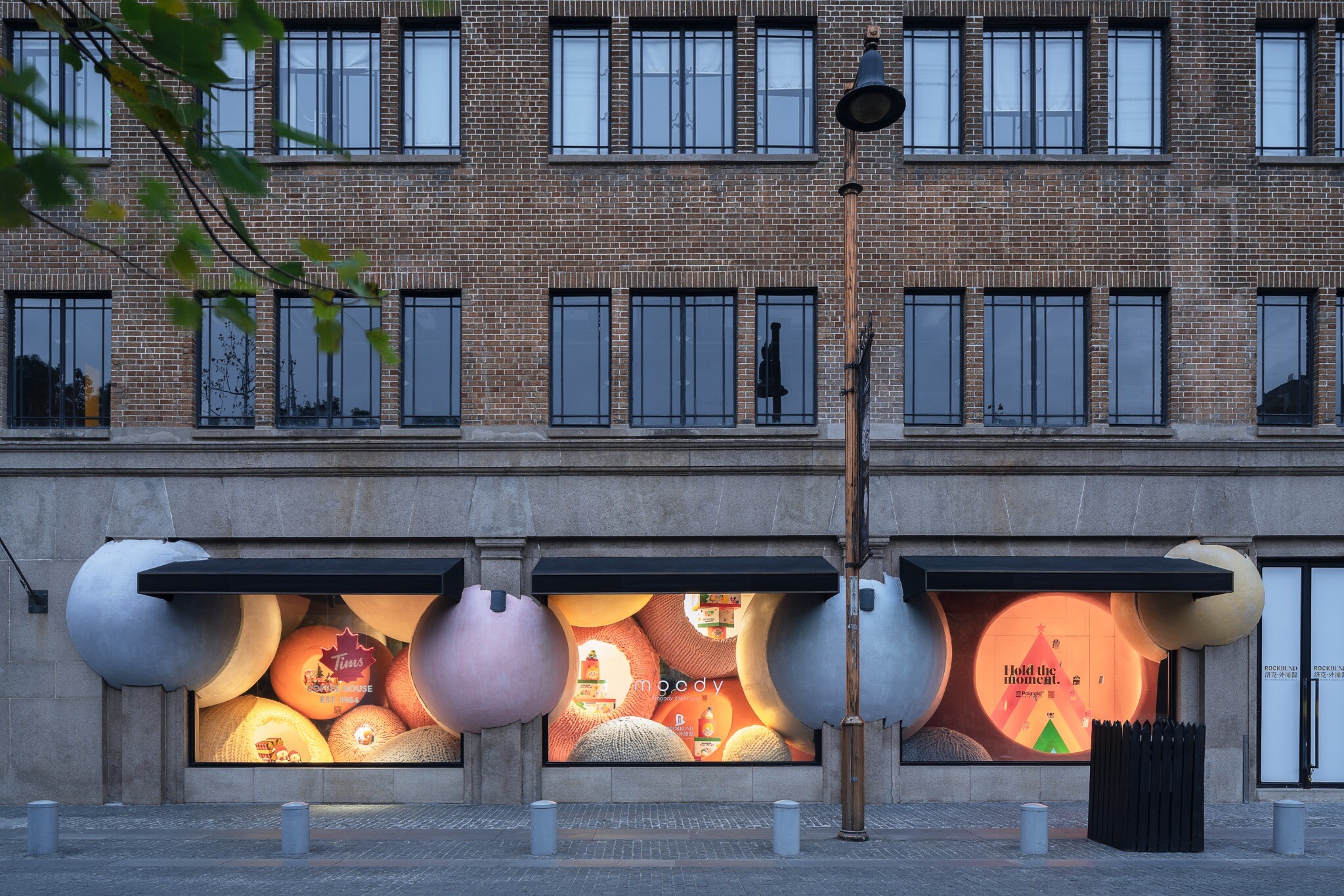 Exterior view of the WAY-out-of-the-box installation, where oversized yarn balls extend outward from glass windows and create a surreal contrast with the Lyceum Building facade.