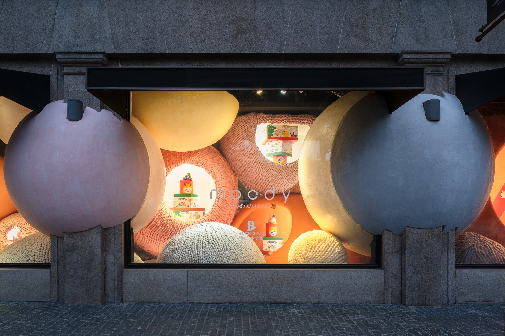 moody Christmas gift boxes displayed inside the spherical space of the central window, combined with oversized yarn balls to create a brand display scene.