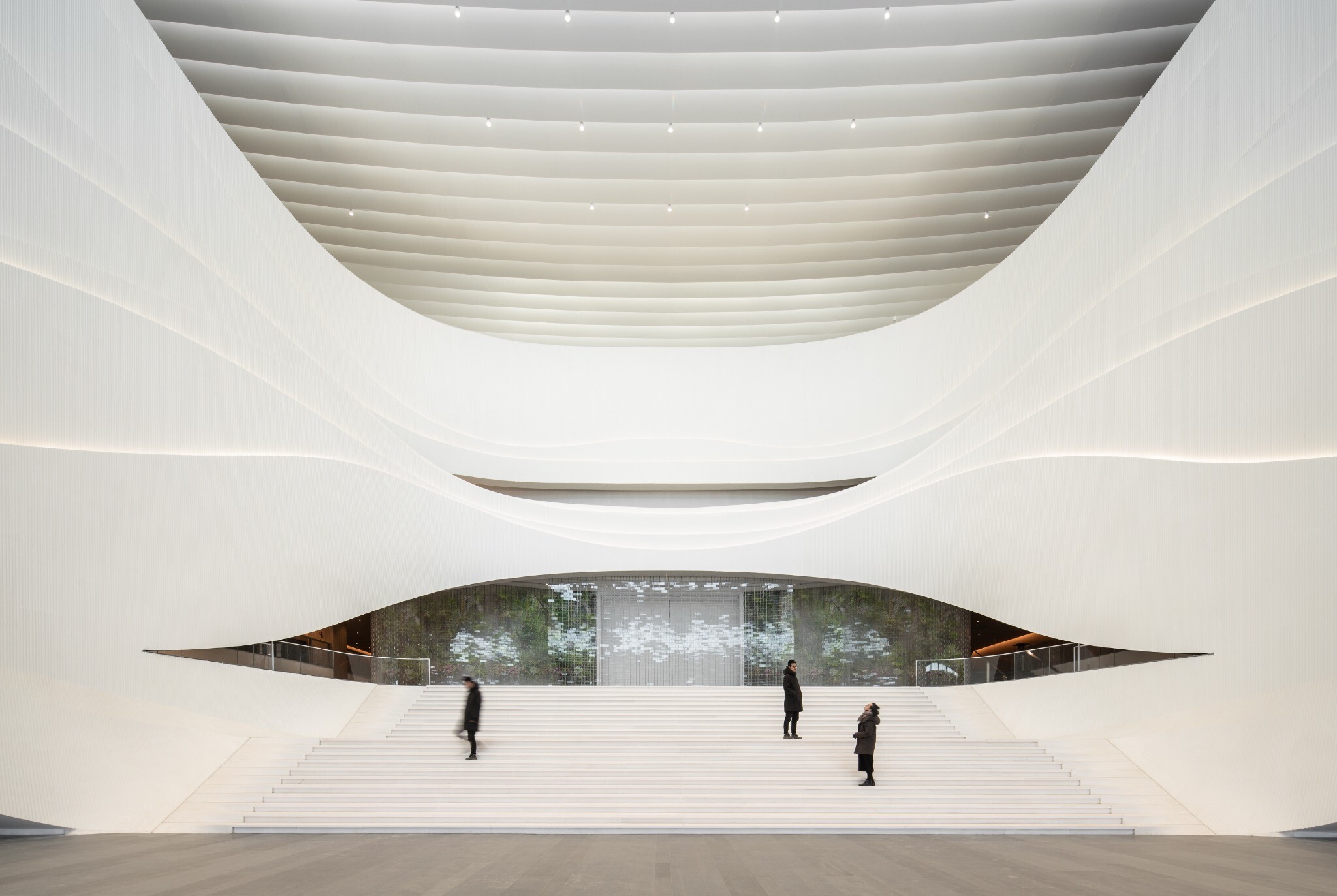 Main visual of the West Wing Art Museum atrium, showing white wing-like balconies, the central stair, natural daylight, and gallery entrances on both sides.