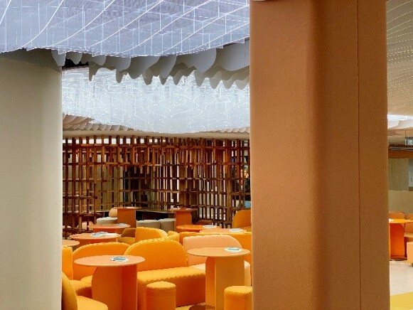 Library and activity area showing the visual connection among book zones, orange activity furniture, and shared space.