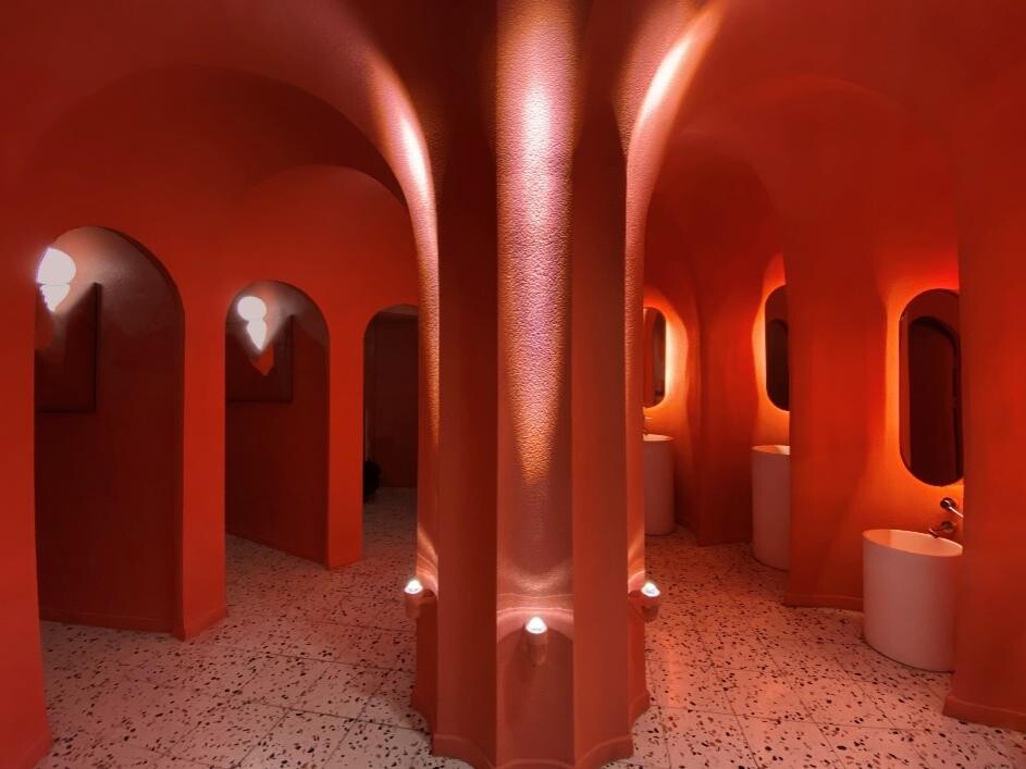 Magenta restroom with enclosing structures and arched openings forming a theatrical, child-friendly space.