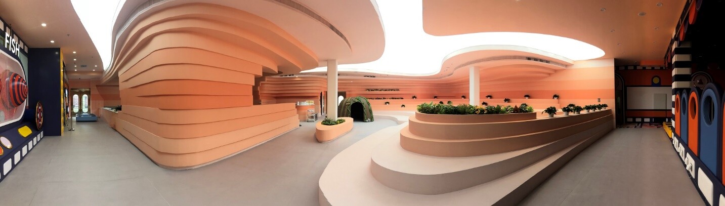 Panoramic view of the first-floor open space, showing curved surfaces, stepped seating, and the entrance transition.