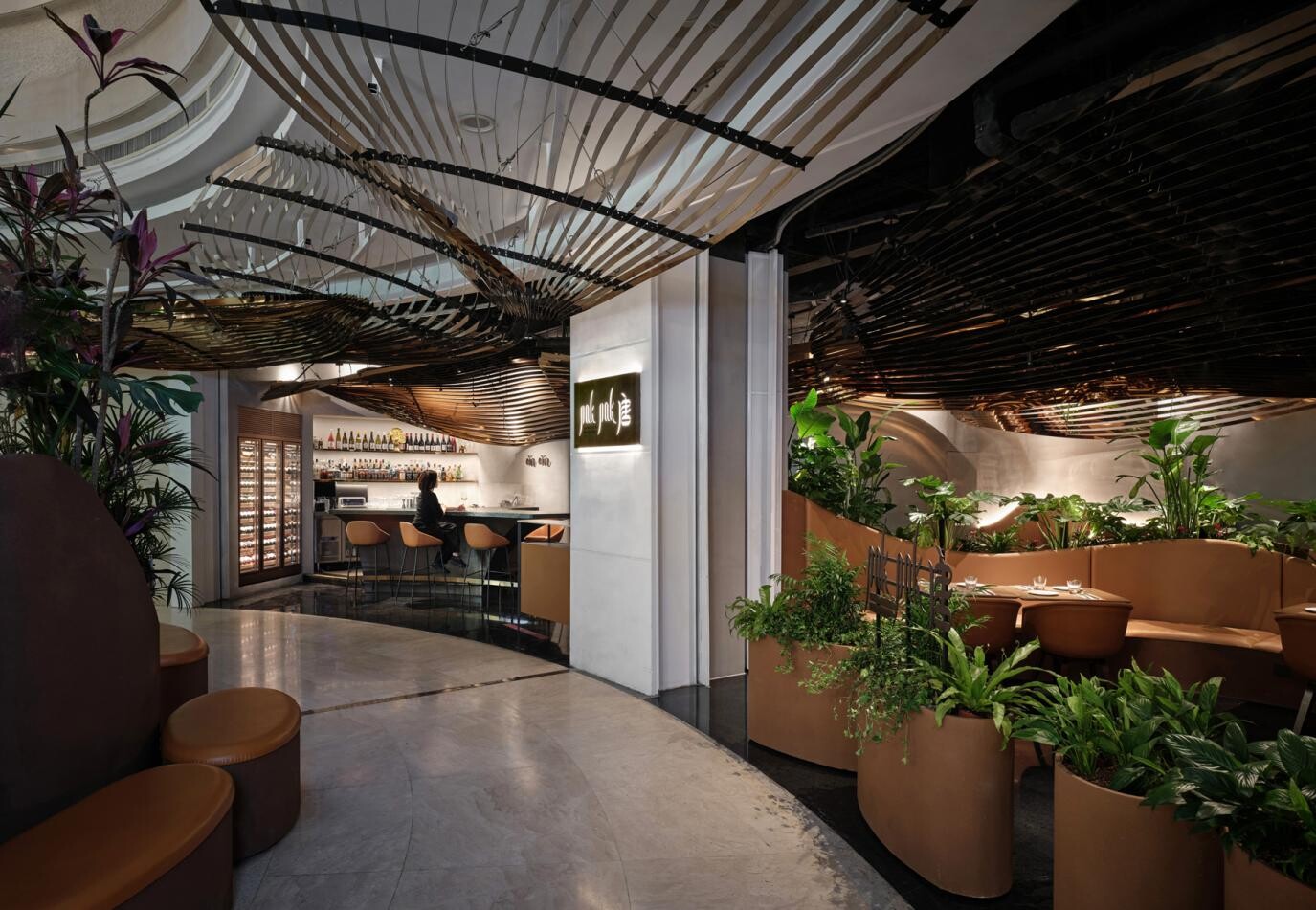 View from the entrance toward the restaurant interior, where the roof installation, bar, and dining area form a continuous spatial guide from the mall public area.