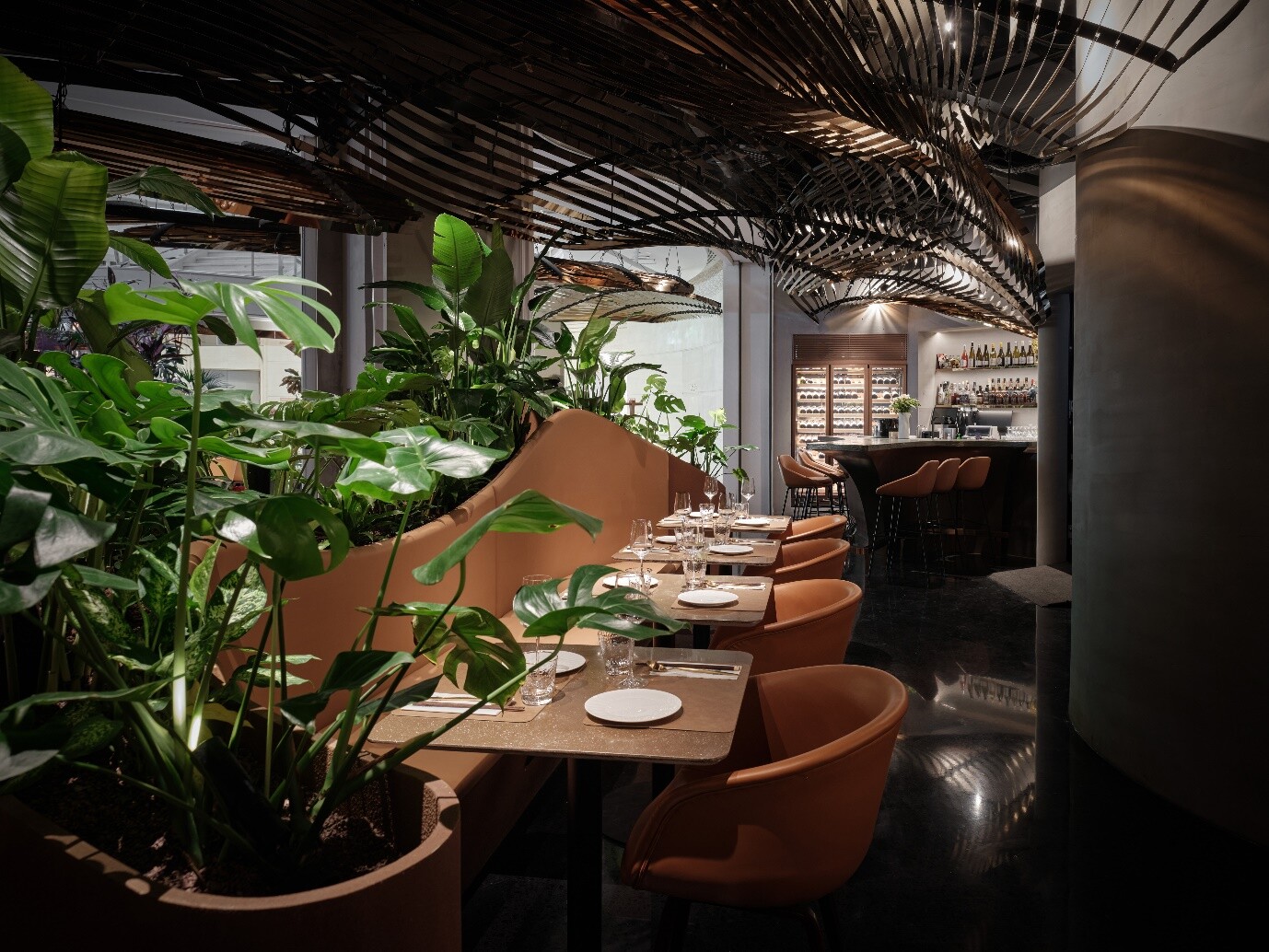 Dining seats wrapped by planters and vegetation, forming a semi-private dining environment close to nature.